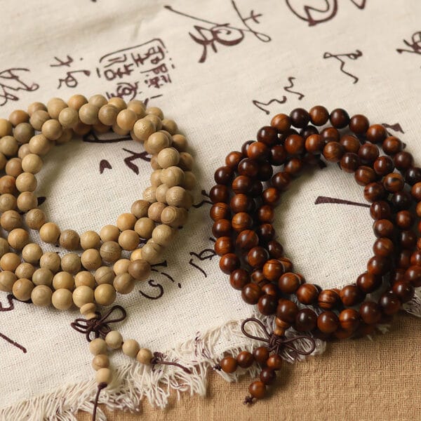 Two wooden bead necklaces, one light and one dark, rest on a fabric background. Wholesale wooden beads.
