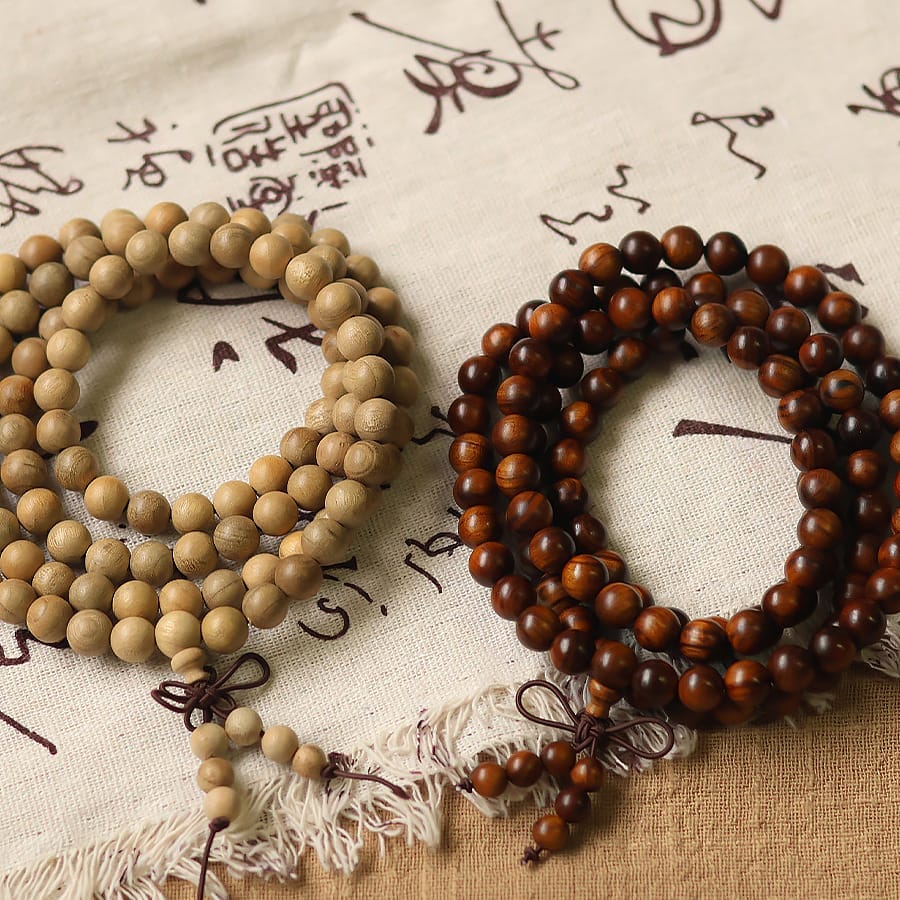 Two wooden bead necklaces, one light and one dark, rest on a fabric background. Wholesale wooden beads.