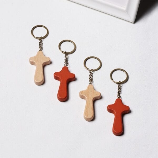 Four wooden cross keychains, two natural and two terracotta, displayed on a white surface. Custom wood cross keychains.
