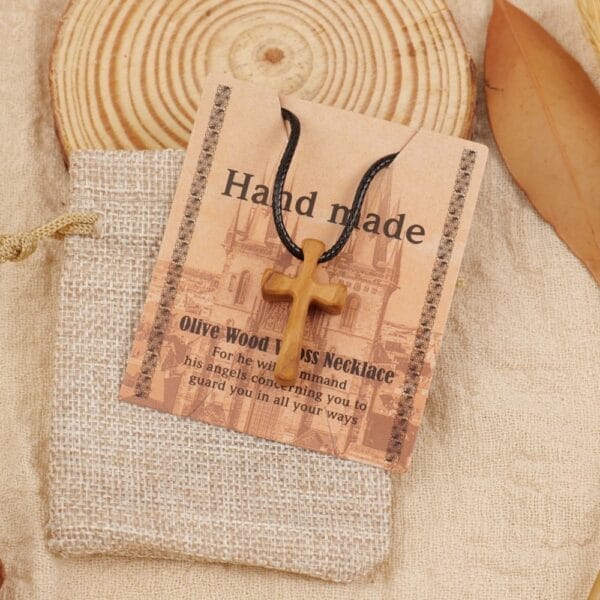 Handmade olive wood cross necklace pendant, Christian jewelry. Features a simple wooden crucifix on a black cord.