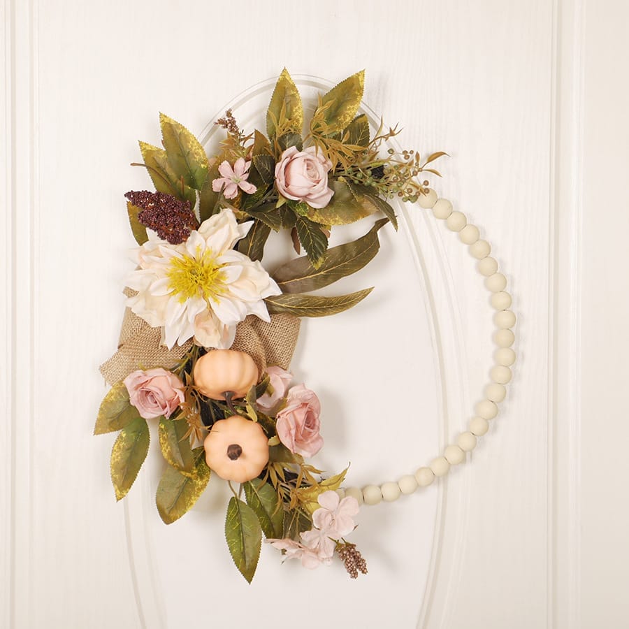 wooden floral wreath with blush roses, pumpkins, and a beaded wooden base. Wholesale laser-cut decor available.