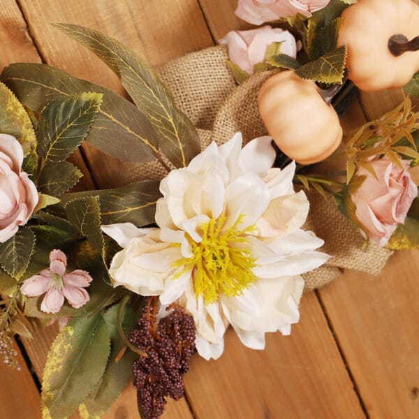 Close-up of autumnal floral wreath with pumpkins and roses. Wholesale laser-cut decor.
