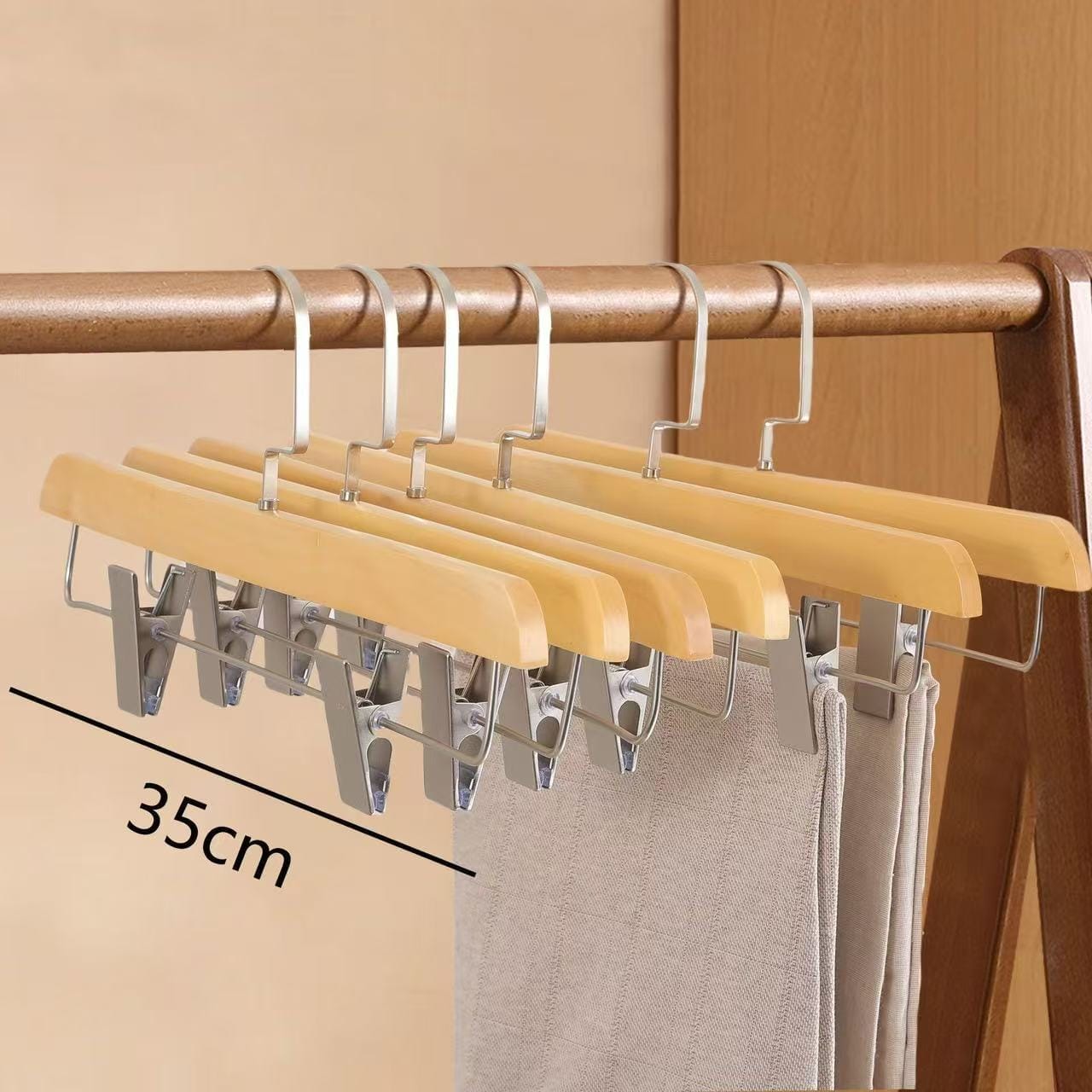 Set of five wooden pants hangers with silver clips, ideal for closet organization. 35cm wide.