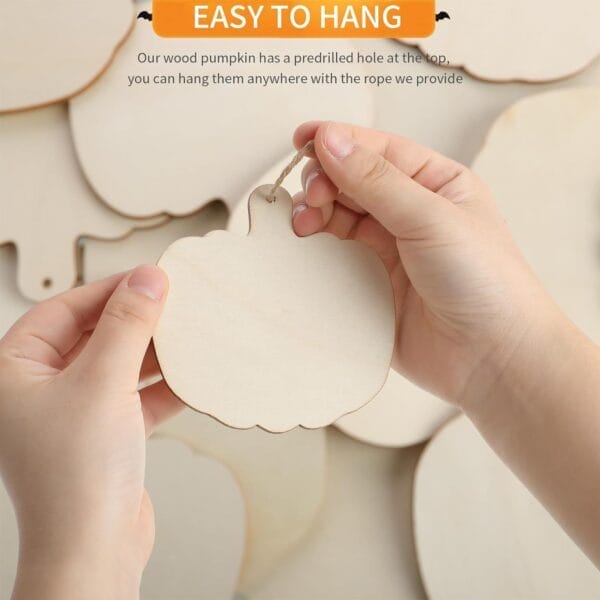 Hands holding a wooden pumpkin cutout with a jute rope, ready to hang. Halloween DIY decoration.