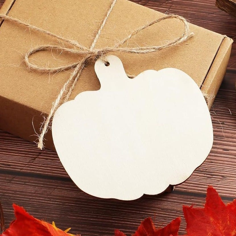 Wooden pumpkin cutout tied with twine to a brown package. Halloween DIY craft supply.
