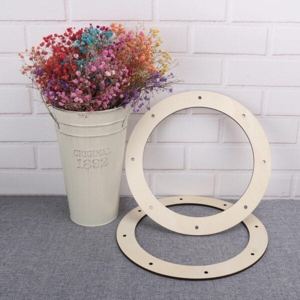 Two unfinished wooden wreath rings with pre-drilled holes, beside a vase of flowers. Wholesale wooden wreath frames.