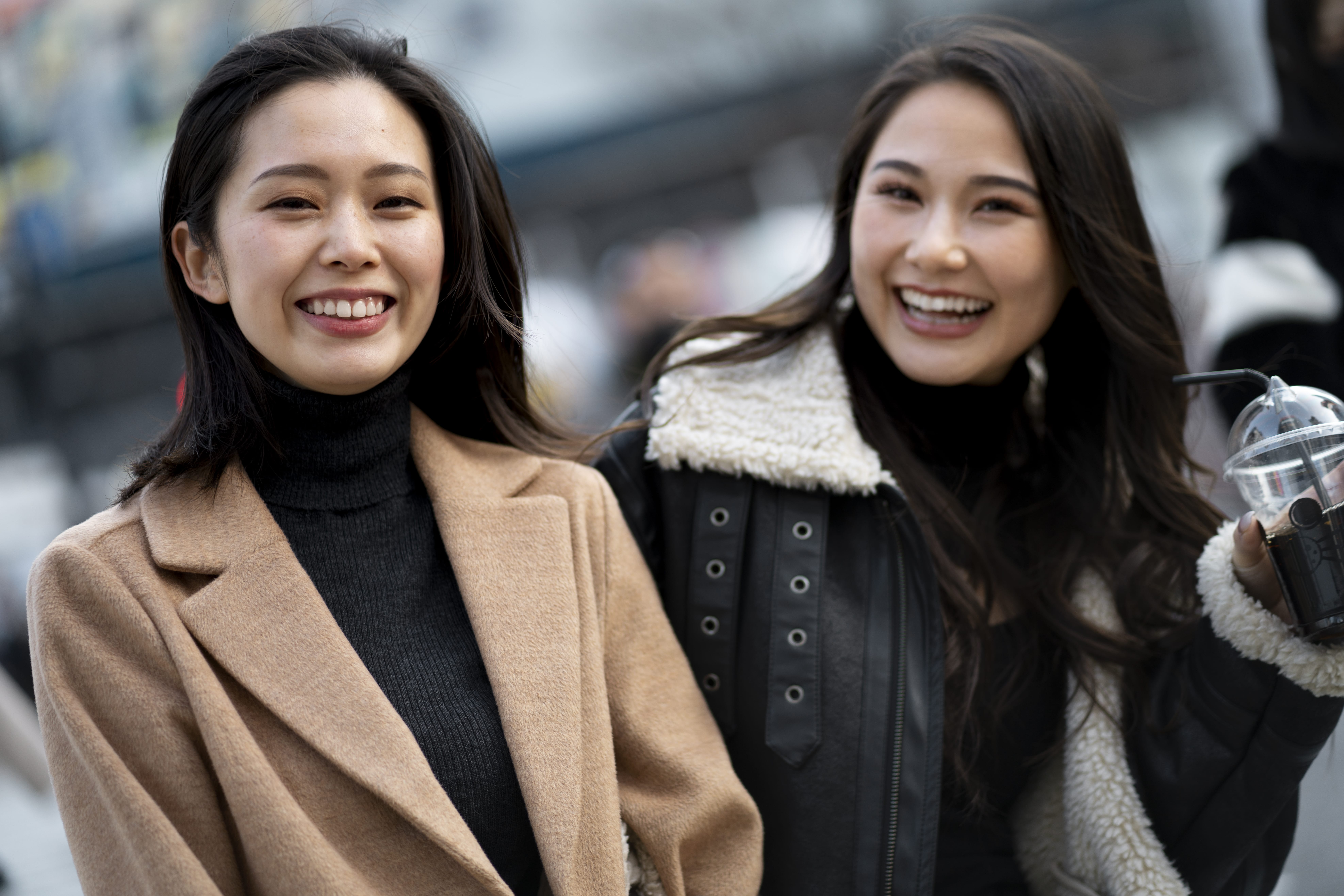 Two women smiling outdoors in stylish winter coats