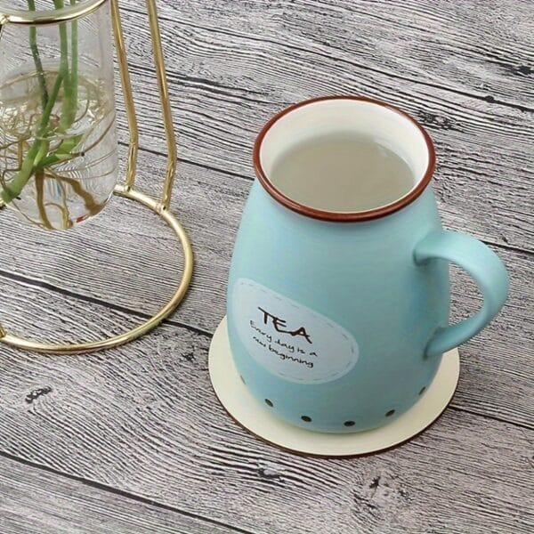 Natural wood disc coaster under a light blue ceramic tea mug. The mug features the text "TEA, Every day is a new beginning".