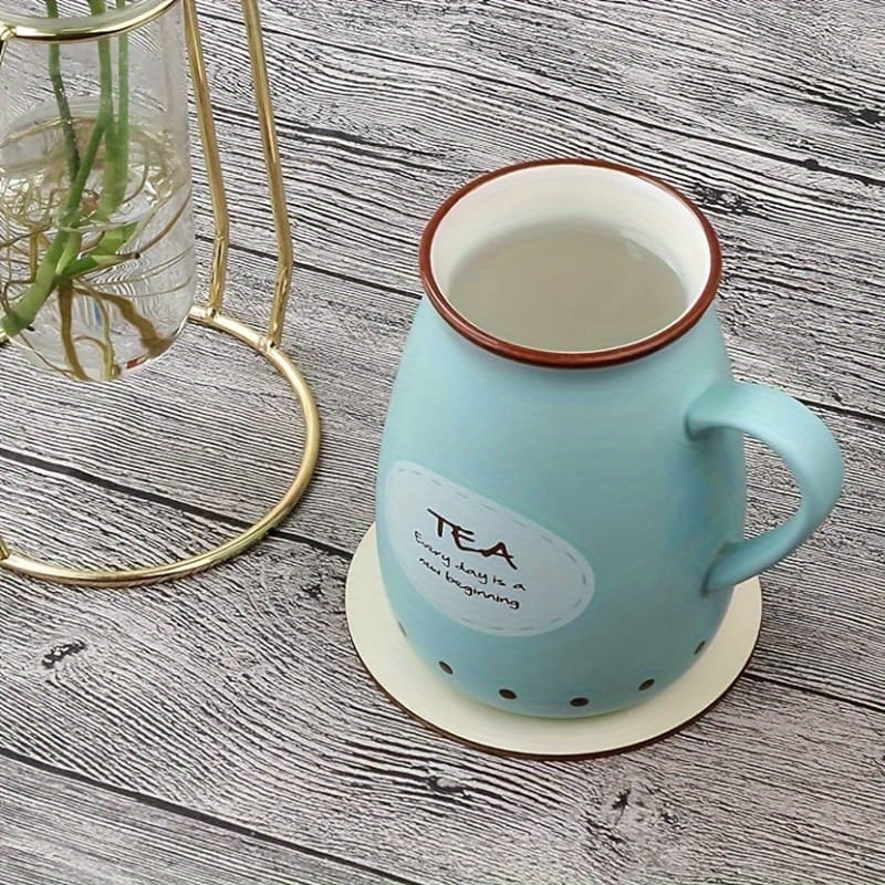 Natural wood disc coaster under a light blue ceramic tea mug. The mug features the text "TEA, Every day is a new beginning".