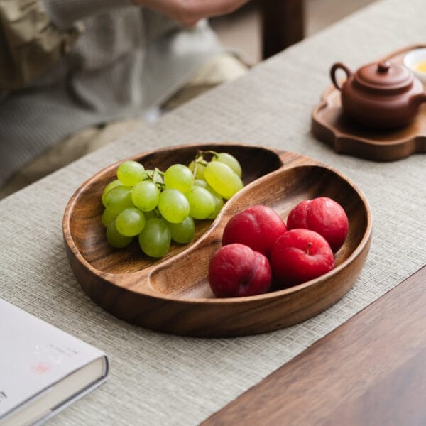 Two-compartment wooden bowl, perfect for snacks or fruit. Features green grapes and red plums.