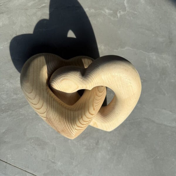 Intertwined wooden hearts sculpture; handcrafted wood carving, perfect for home decor. Wholesale and custom options available.