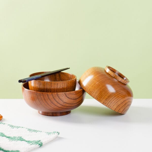 Manufacturer Wholesale Wood Heat-Resistant Wooden Bowl Set: Three nested dark brown wooden bowls with chopsticks.
