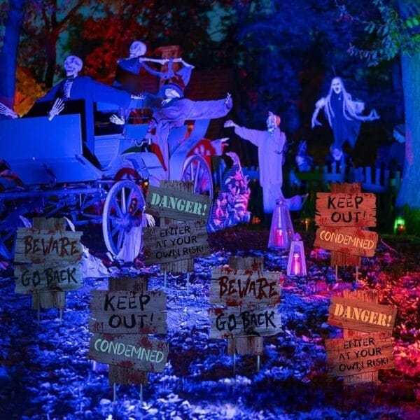 Halloween decorations: Spooky yard signs (Beware, Danger, Keep Out), skeleton props, ghostly carriage, create a haunted scene.