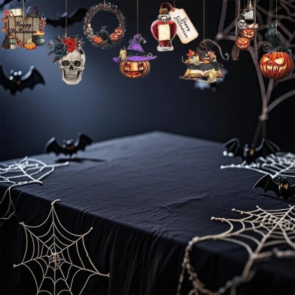 Halloween table decorations with hanging skull, pumpkins, and witch ornaments over black cloth and spiderwebs