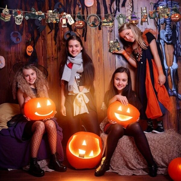 Children in Halloween costumes holding illuminated carved pumpkins, surrounded by festive decorations