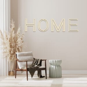 Modern living room with beige armchair, pampas grass, and "HOME" wall art.