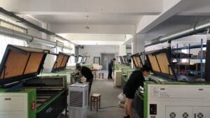 Laser cutting workshop with workers using machines. Manufacturing process.