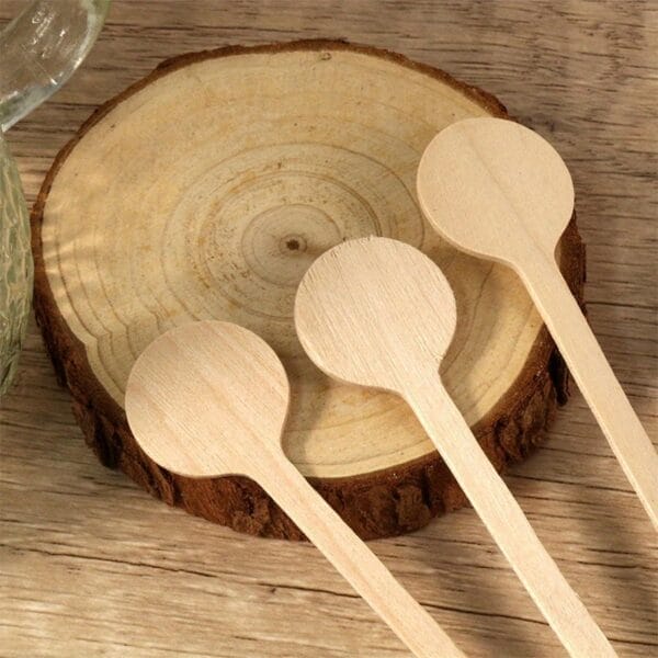 Custom wooden stir sticks, eco-friendly disposable spoons, perfect for parties and events on a wood slice.