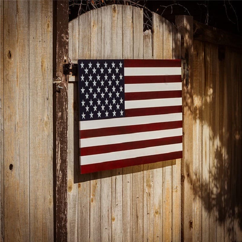 Handmade wooden American flag art hanging on rustic fence