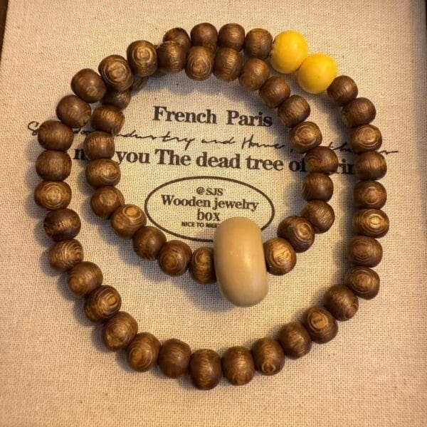 Wooden bead bracelet with yellow accent beads and a neutral-toned centerpiece