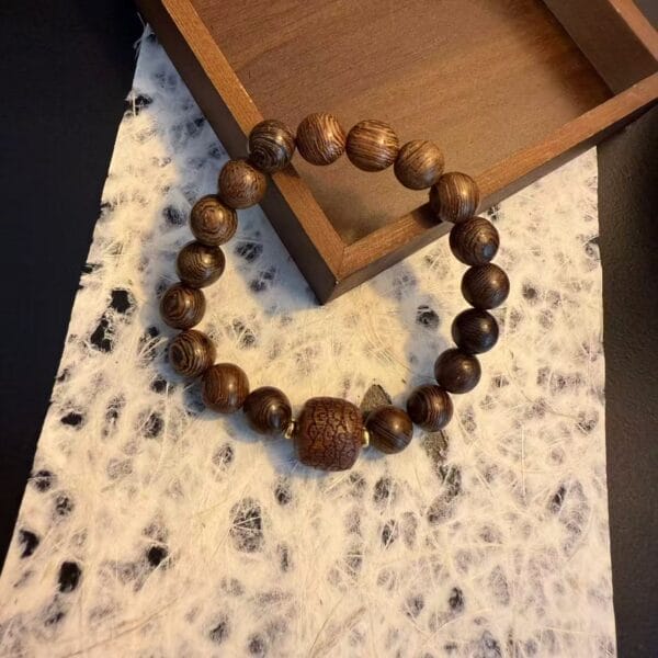 AUTO-DRAFT: Wooden beaded bracelet with square patterned centerpiece.
