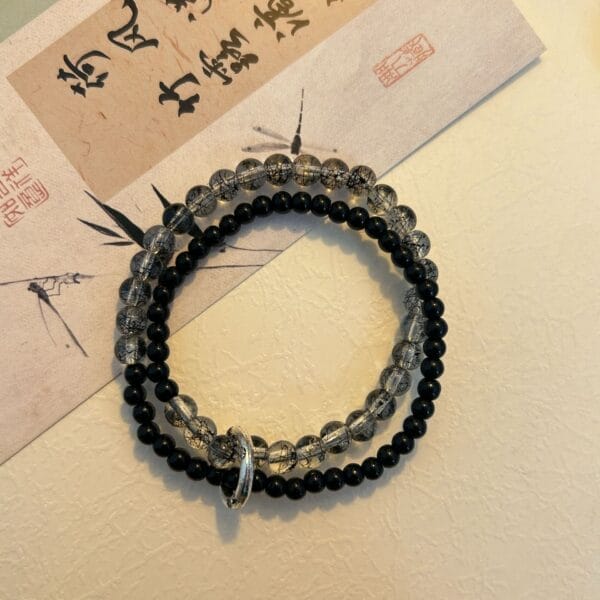 Two beaded bracelets: Black beads and clear beads with black inclusions, jewelry.