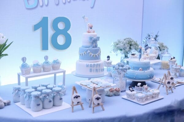 Baby blue 18th birthday dessert table with tiered cake, cupcakes, and cookies