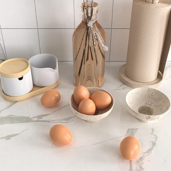 Eggs on marble countertop near paper towels, vase, and bowls. Kitchen still life.