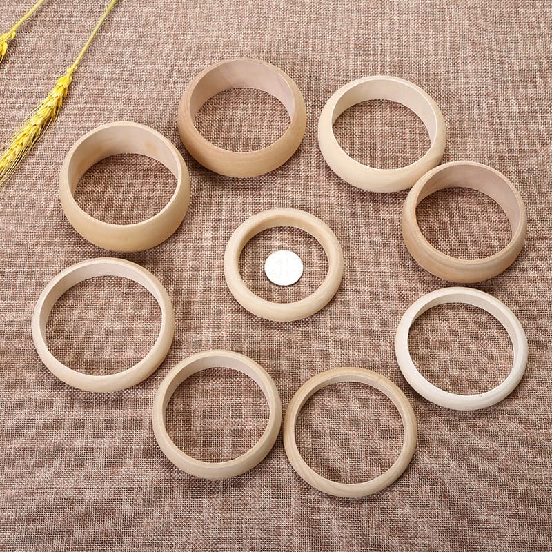 Assorted wooden bangles in natural tones, varying in size and width, displayed on burlap