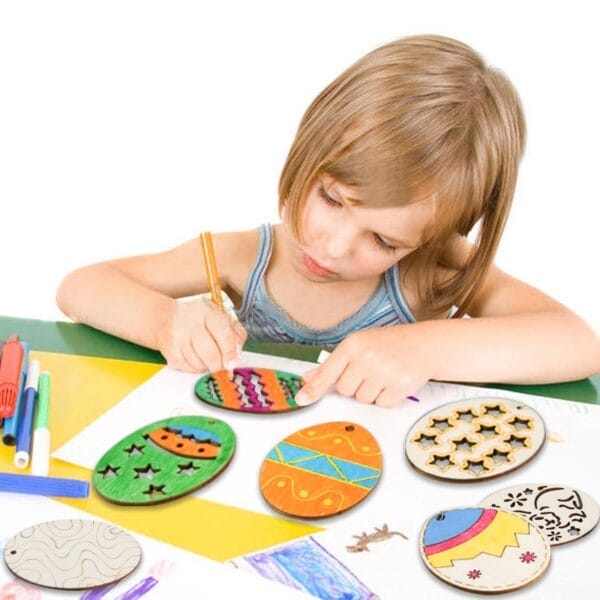 Girl coloring wooden Easter egg cutouts with markers on a table. Easter craft project.
