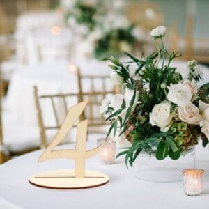 Rustic Wood Table Number 4. Custom wooden wedding table number on a table with flowers and candles.