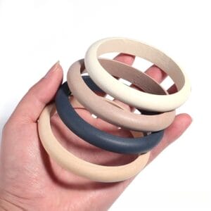 Wholesale Wooden Bangle Bracelets: Polished natural wood bangles in multicolor finishes held in hand.
