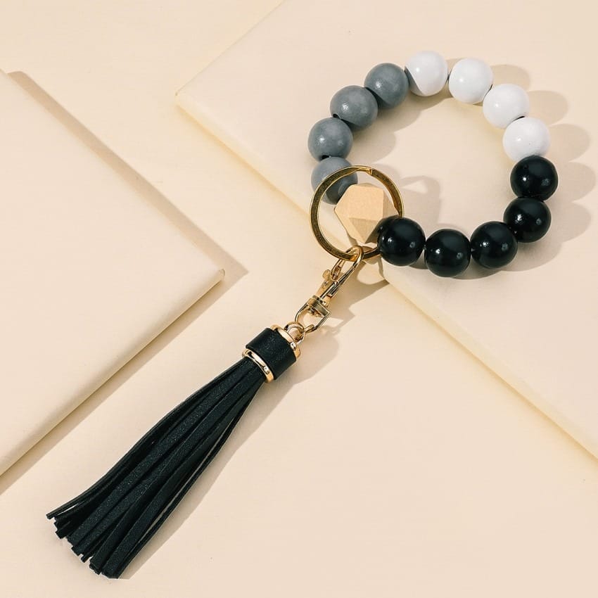 Beaded bracelet keychain with gray, white, and black beads, plus a black tassel.