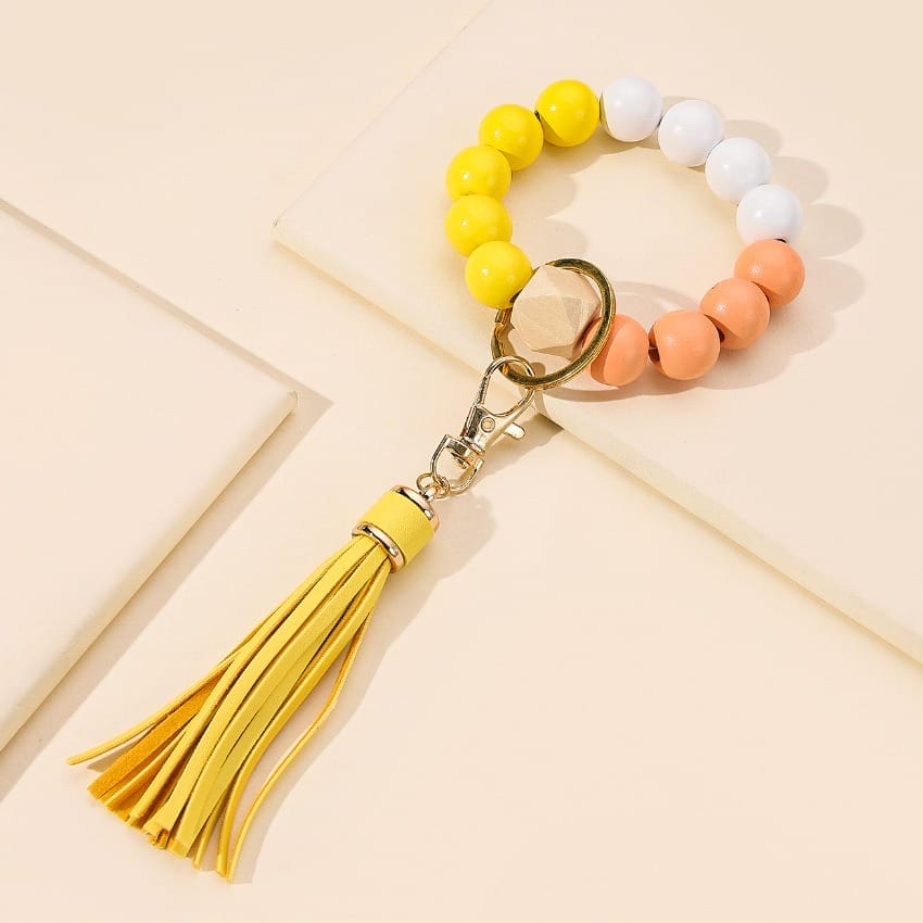 Bracelet key ring with yellow, white, peach wooden beads and yellow tassel.