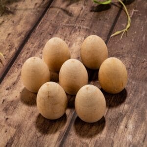 Seven unfinished wooden craft eggs on a rustic wooden surface.