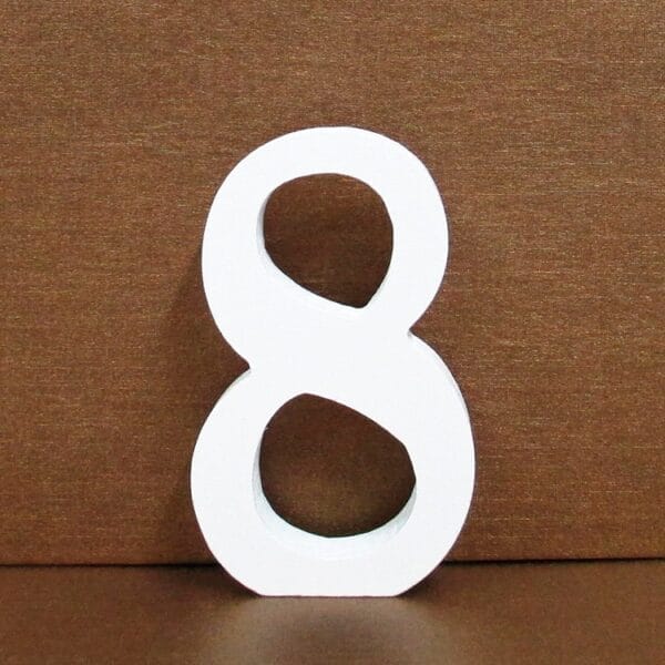 White number 8 standing on a brown surface, against a brown background.
