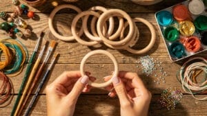 Hands holding a wooden bangle, surrounded by craft supplies for DIY jewelry styling.