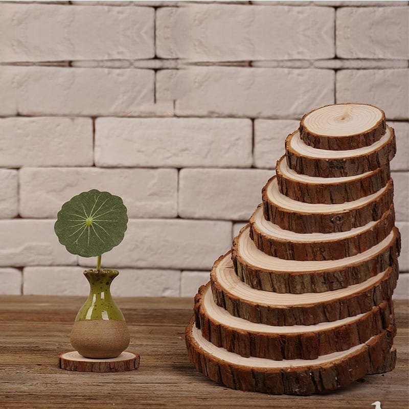 Stacked wooden tree slices forming a pyramid, plus vase on wood stand. Rustic decor.
