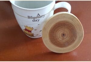 Mug with Winnie the Pooh next to a round wooden coaster.