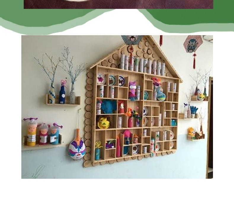 House-shaped wooden shelf displaying various colorful crafts and decorative items.