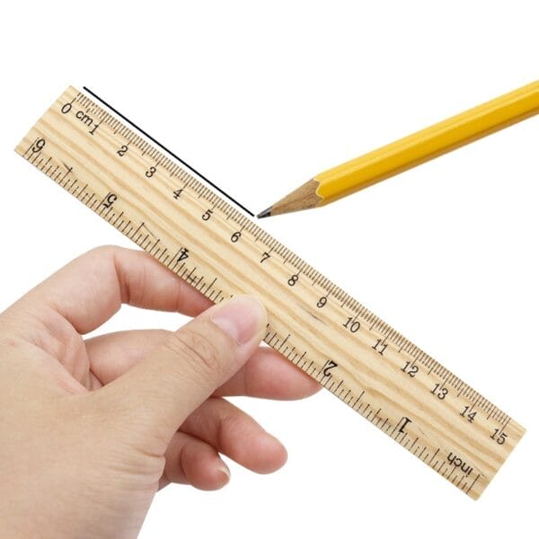 Wooden ruler in hand with pencil. Centimeter and inch markings shown.