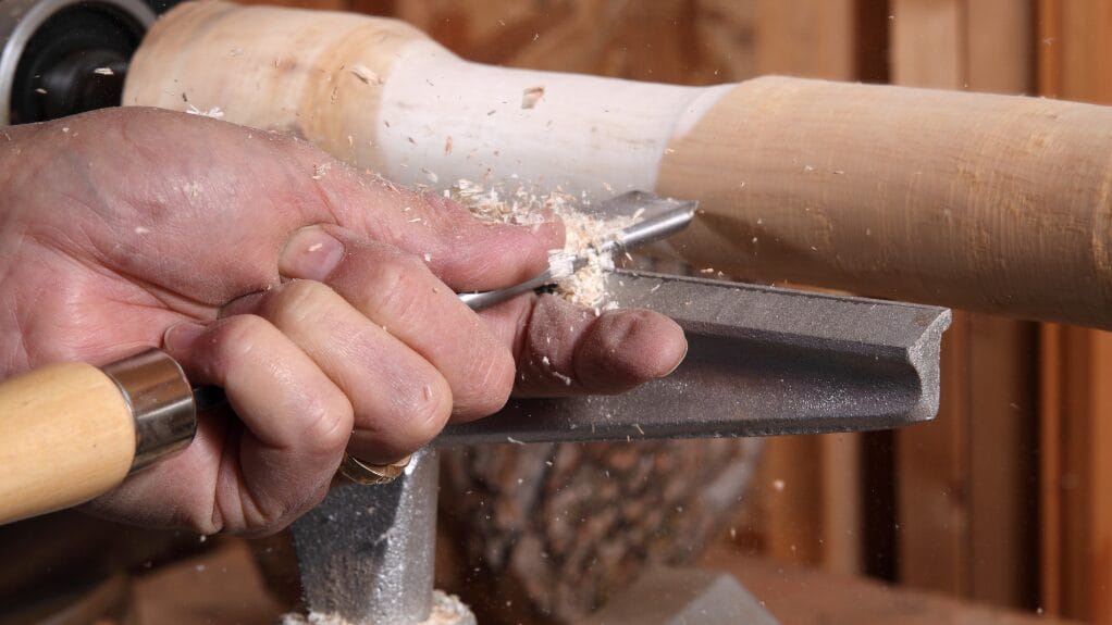 Wood Turning Craft: wood turner shaping wood on a lathe with a chisel.