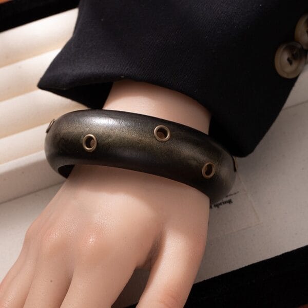 Black Wooden Bangle Cuff: Wide studded wooden bracelet on wrist. Statement jewelry.