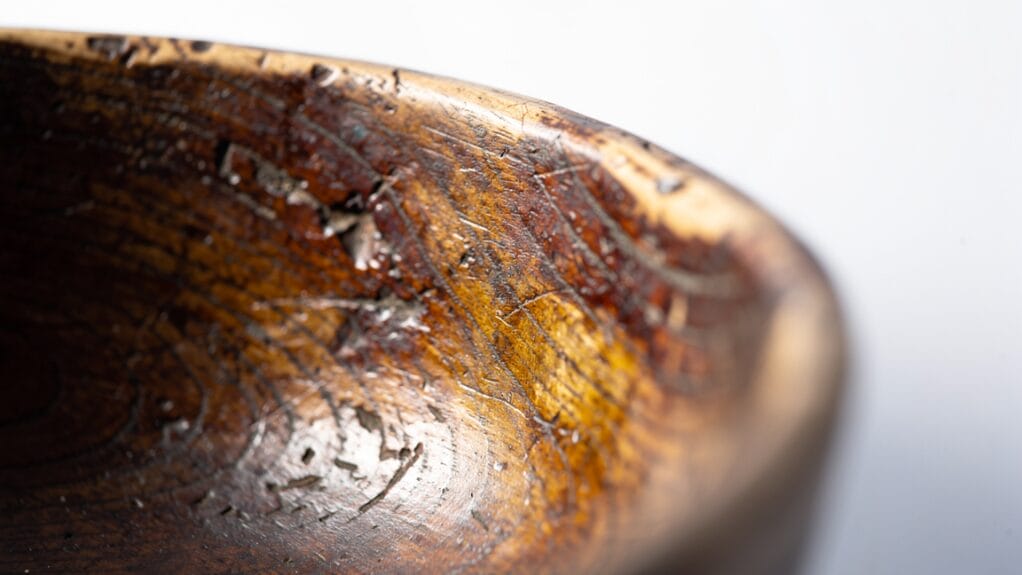 Close-up of an antique wooden bowl's textured surface, showing grain and wear.