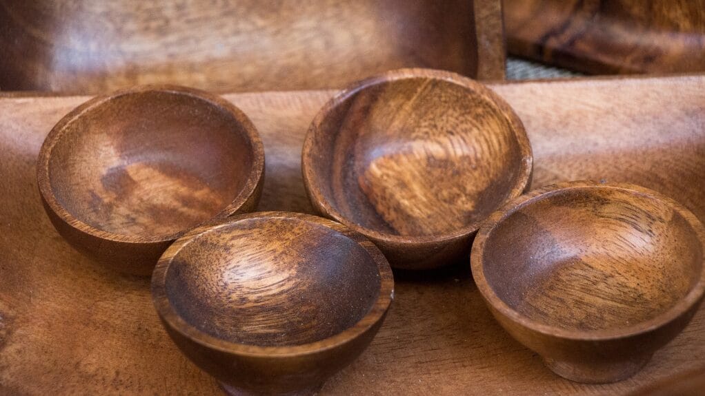 Four small wooden bowls on a larger wooden tray, showcasing natural grain and texture.