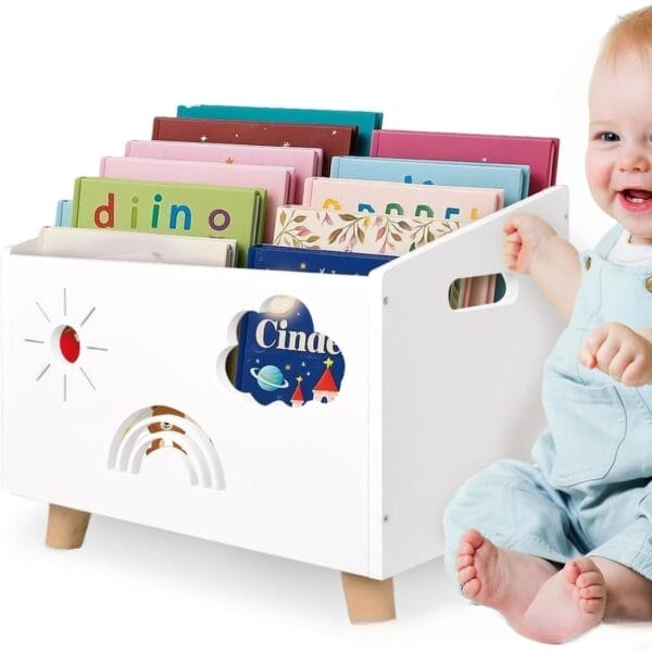 White wooden bookshelf for kids with sun, rainbow, cloud cutouts, filled with colorful books, next to a baby.