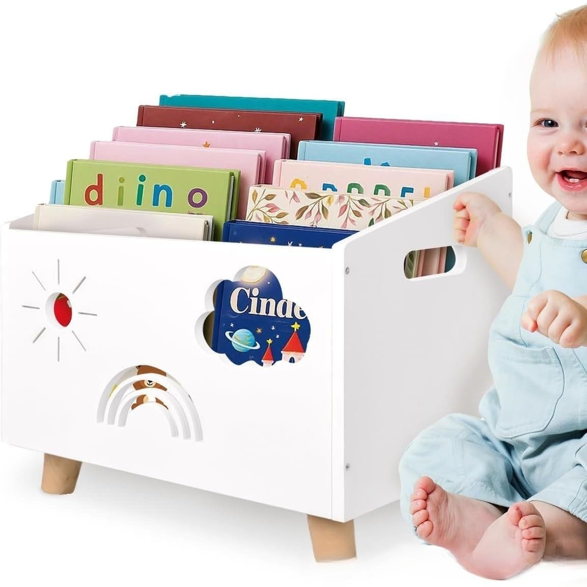 White wooden bookshelf for kids with sun, rainbow, cloud cutouts, filled with colorful books, next to a baby.
