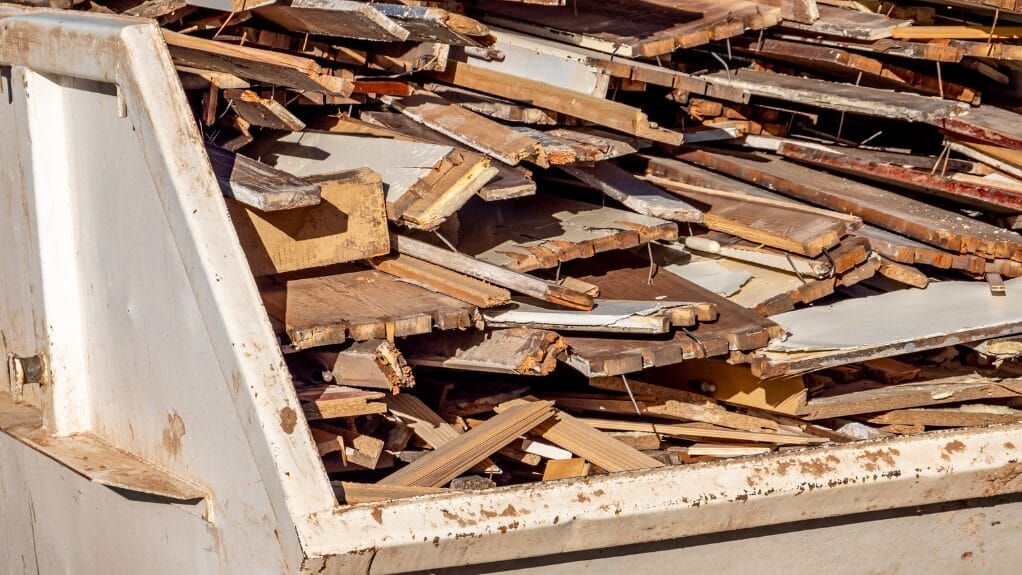 Waste wood in a metal dumpster, ready for recycling. Is wood a recyclable material?