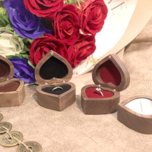 Heart-shaped wooden ring boxes with rings inside, roses in background.