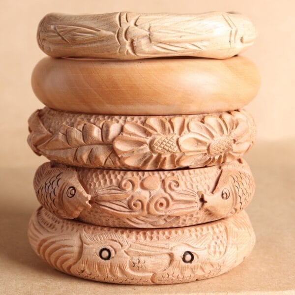Stack of five intricately carved wooden bangles featuring floral and animal designs.